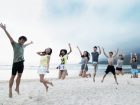 砂浜でジャンプをする男女8人のグループ