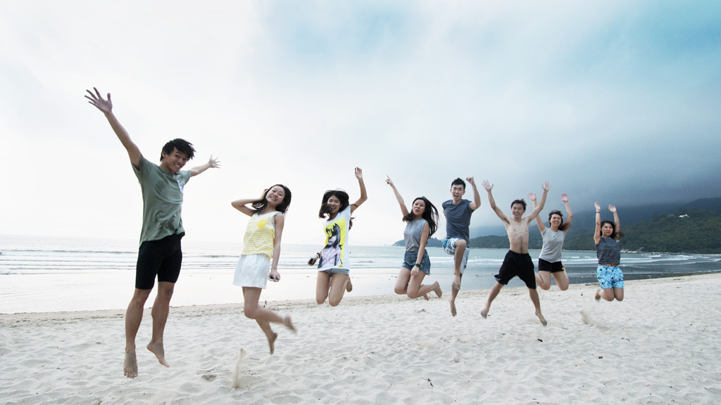 砂浜でジャンプをする男女8人のグループ