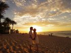 ハワイに浜辺で夕日を背にキスする幸せカップル