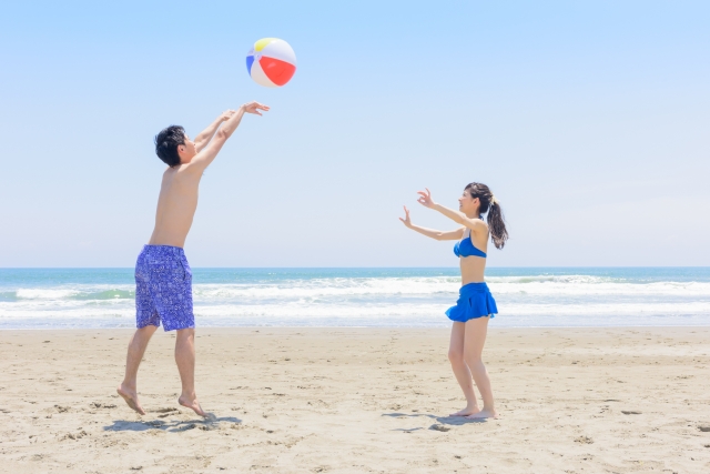 浜辺で楽しそうにビーチーボールで遊んでいるカップル